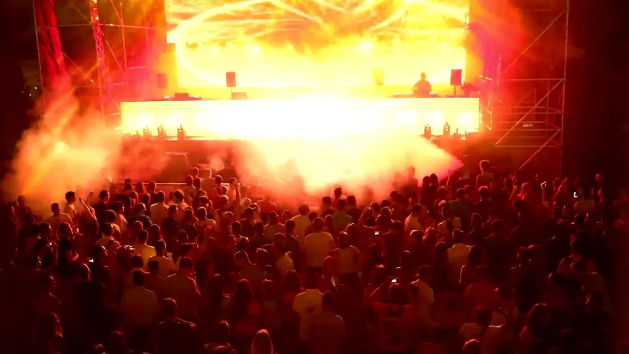 Escenario de un festival visto por encima del público, con humo naranja